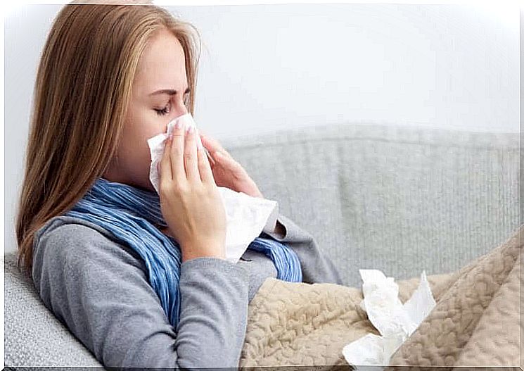 A woman lying blowing her nose with a cold